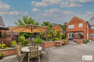 a patio with a table and chairs and an umbrella at Silver Stag Properties Large 4 bed Property in Markfield
