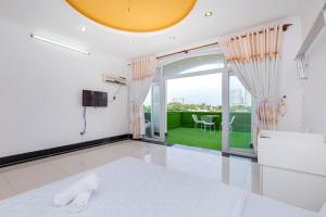 a white bedroom with a bed and a large window at Villa Hai An in Vung Tau
