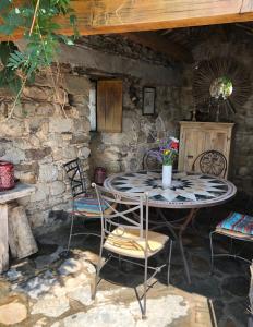 stół i krzesła przed kamiennym budynkiem w obiekcie Mas Des Terrasses w mieście Aujac
