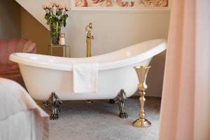 a white bath tub in a bathroom with a vase of flowers at La Rose Residence in Mikołajki