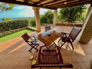 Une table et des chaises en bois sont disponibles sur la terrasse. dans l'établissement villa Mirtilla, à Villasimius