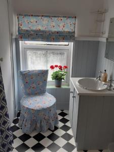 La salle de bains est pourvue d'une chaise, d'un lavabo et d'une fenêtre. dans l'établissement Rose Cottage, à Telford