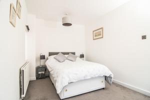 a white bedroom with a bed with white sheets and pillows at ALTIDO Family house with courtyard in Hoylake in Hoylake