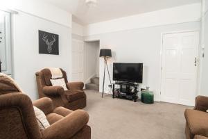 a living room with two chairs and a flat screen tv at JOIVY Family house with courtyard in Hoylake in Hoylake