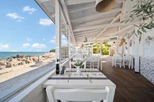 ein Restaurant am Strand mit weißen Tischen und Stühlen in der Unterkunft Riviera Beach Hotel & SPA, Riviera Holiday Club - All Inclusive & Private Beach in Goldstrand