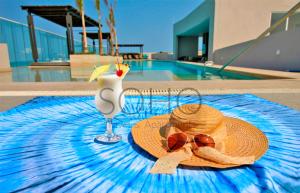un sombrero de paja y gafas de sol en una mesa junto a la piscina en Apartamentos Reserva del Mar - Frente al Mar by SOHO, en Santa Marta