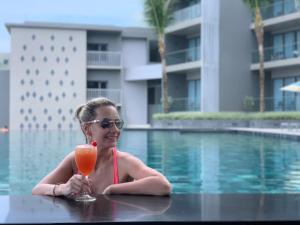 a woman in a swimming pool holding a drink at Oceanfront Beach Resort - SHA Extra Plus in Patong Beach