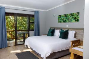 1 dormitorio con 1 cama grande y balcón en Ndalo Lodge Mbombela en Nelspruit