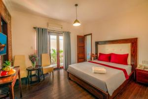 Un dormitorio con una cama con almohadas rojas y una mesa. en Calm House Hotel Hoi An 1, en Hoi An