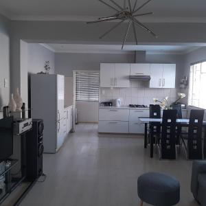 una cocina con armarios blancos y una mesa con sillas. en The Cradle's Rest Guest House en Krugersdorp
