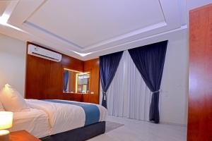 a bedroom with a large bed with blue curtains at اجنحه كنزان in Al Mubarraz