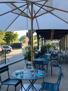 un groupe de tables et de chaises sous un parapluie dans l'établissement Hôtel Logis Restaurant La Fontaine, à Mantry