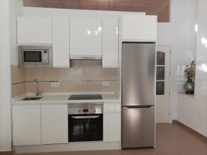 a kitchen with white cabinets and a stainless steel refrigerator at El Rincón de Paula in Baena