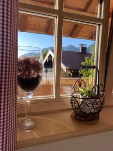 um copo de vinho sentado no parapeito da janela em Ferienwohnung Schreiner-Viehhausen em Grassau