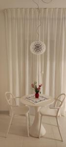 una mesa blanca con 2 sillas y un jarrón con flores en Casa Pellegrino en Polignano a Mare