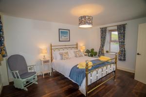 a bedroom with a bed and a chair and a window at The Cottages @ Slievenisky in Ballyward
