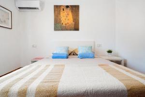 1 dormitorio blanco con 1 cama grande con almohadas azules en Charming Mediterranean house with private jacuzzi sea and mountain views en Miami Platja