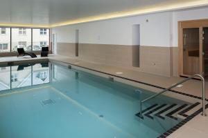 a large swimming pool with blue water in a building at 6 Woolacombe West - Luxury Apartment at Byron Woolacombe, only 4 minute walk to Woolacombe Beach! in Woolacombe