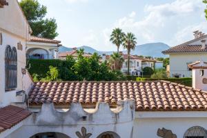 un edificio con techo de baldosa y montañas de fondo en Charming Mediterranean house with private jacuzzi sea and mountain views en Miami Platja