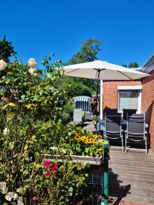 eine Terrasse mit Stühlen, einem Sonnenschirm und Blumen in der Unterkunft Ferienhaus am Südstrand Borkum in Borkum