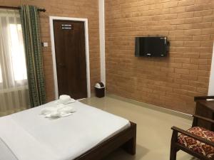 a room with a bed and a tv on a brick wall at Hotel Varsha in Kekirawa
