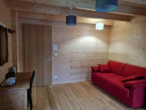 un soggiorno con divano rosso e parete in legno di Chalet Gaspard a Valtournenche
