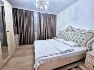 a bedroom with a large bed and a chandelier at Очень уютная квартира рядом с посольством США in Almaty