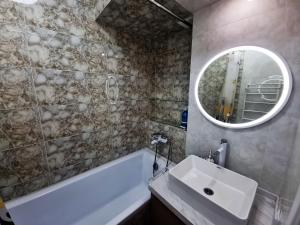 a bathroom with a sink and a tub and a mirror at Очень уютная квартира рядом с посольством США in Almaty