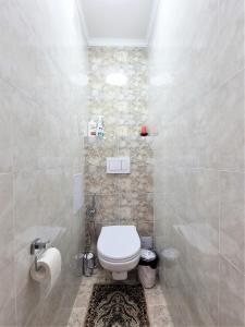 a white bathroom with a toilet and a shower at Очень уютная квартира рядом с посольством США in Almaty