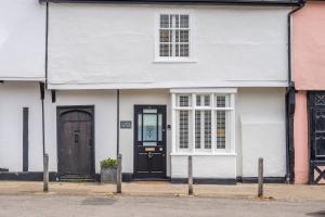 a white house with a black door and windows at Utterly divine romantic retreat in brilliant village - Tudor Cottage in Sudbury