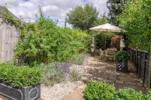 a garden with a table and an umbrella at Utterly divine romantic retreat in brilliant village - Tudor Cottage in Sudbury