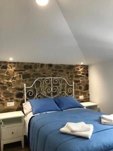 una camera con letto blu e parete in pietra di Casa Cea a Melide