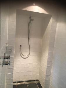 een douche in een badkamer met witte tegels bij B&B 't Varkenshuus in Aalten