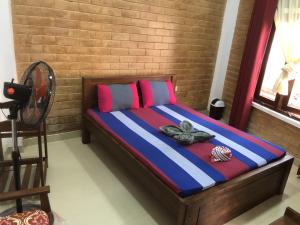 a bedroom with a bed with blue and pink pillows at Hotel Varsha in Kekirawa
