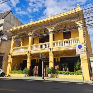 a yellow building with plants in front of a street at Sittisang1920 in Kanchanaburi