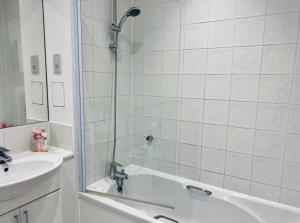een badkamer met een douche, een wastafel en een bad bij Cloud9SA at The Charles Chertsey in Chertsey