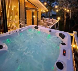 un bain à remous avec des lumières vertes dans une arrière-cour dans l'établissement Gower Villa Luxury Cottage, 2 bedroom en-suite with Hot Tub, à Clynderwen