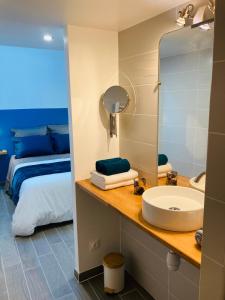 a bathroom with a sink and a bed and a mirror at Le Flocmagny in Chalons en Champagne