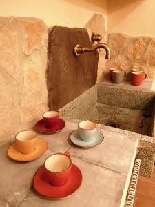 tres tazas y platillos en un mostrador con fregadero en Nel vicolo dei Baci - Casa vacanze al Bacio, en Spello
