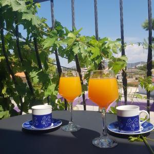 dos vasos de zumo de naranja y dos tazas en una mesa. en jardin kapetanova kuća, en Veli Iž