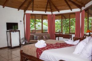 a bedroom with a bed and a tv and windows at Hosteria Orkidea Lodge in Puyo