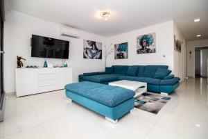 a living room with blue couches and a tv at Luxury Apartment Luna in Vantačići