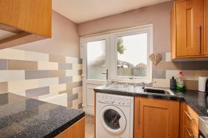 a kitchen with a washing machine and a window at Cosy 2 bedroom flat, with parking & garden in Seaton Delaval