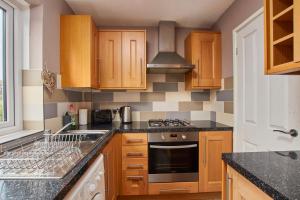 a kitchen with wooden cabinets and a stove top oven at Cosy 2 bedroom flat, with parking & garden in Seaton Delaval