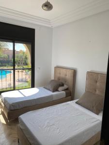 two beds in a bedroom with a view of a pool at Chez balqis atlas golf in Marrakech