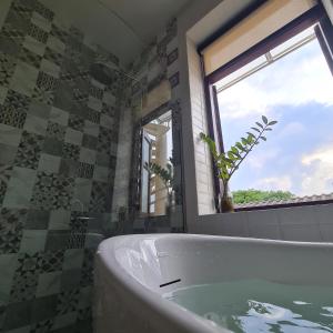 uma casa de banho com uma banheira e uma janela em Sittisang1920 em Kanchanaburi