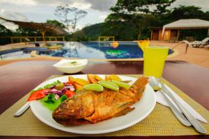 a plate of fish and salad and a drink on a table at Hosteria Orkidea Lodge in Puyo +53 photos