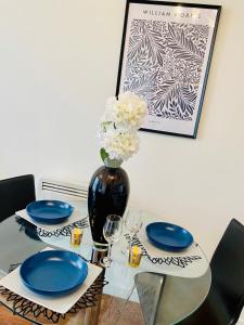 a glass table with blue plates and a vase with flowers at Cloud9SA at The Nankeville Woking in Woking
