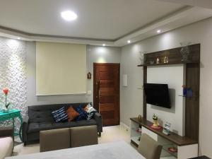 ein Wohnzimmer mit einem Sofa und einem Flachbild-TV in der Unterkunft Casa bem aconchegante! in Ubatuba