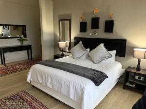 a bedroom with a large white bed and a desk at House Vos in Hermanus